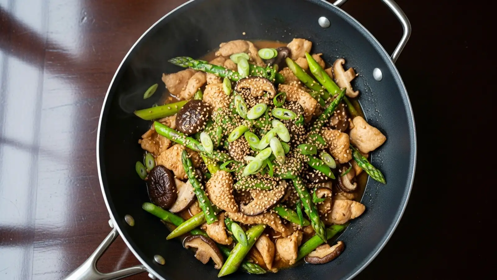 Vibrant ginger chicken stir fry with green asparagus, brown shiitake, and a glossy sauce in a black wok.