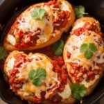 Golden-brown chicken breasts stuffed with cheese and baked in red salsa, garnished with cilantro in a cast iron skillet.