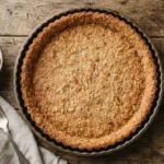 Golden-brown almond coconut tart crust in a fluted tart pan on a wooden surface.